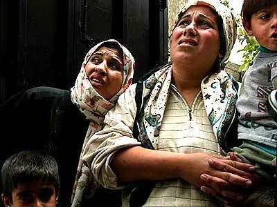 Rashida Dasky, left, and her family watch on Monday as an Israeli helicopter flies over the refugee camp in Jenin. The family waited for the helicopter to pass before running home.