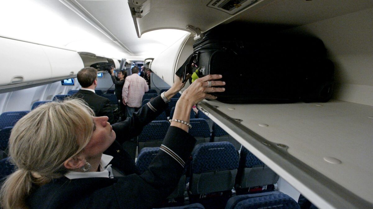 An American Airlines flight attendant demonstrates the overhead baggage area.