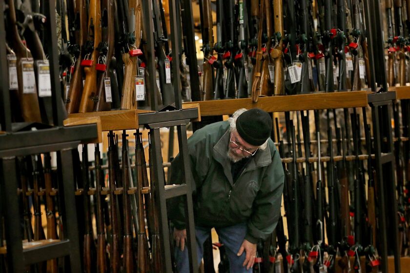 FILE - In this Nov. 29, 2019, file photo, a man looks at the shotgun section of Cabela's while shopping on Black Friday in Hazelwood, Mo. The number of background checks conducted by federal authorities is on pace to break a record by the end of this year. (Christian Gooden/St. Louis Post-Dispatch via AP)