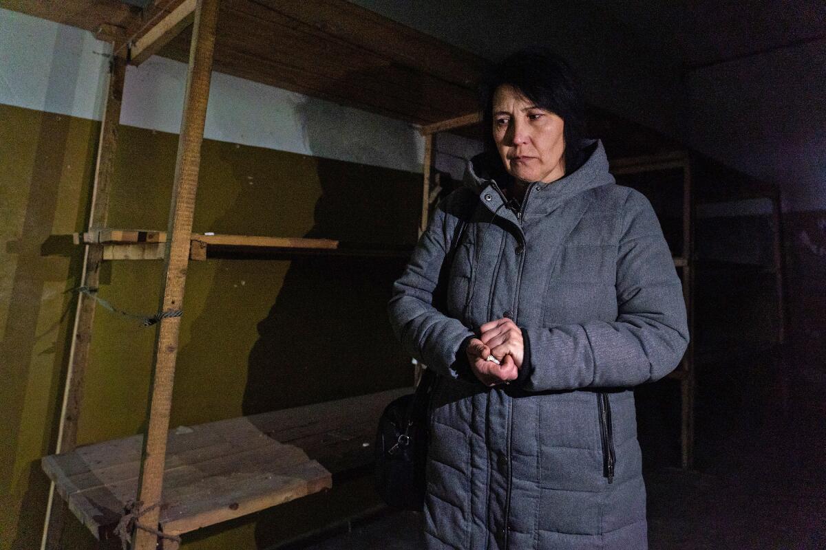 A woman in a coat stands next to wooden bunks