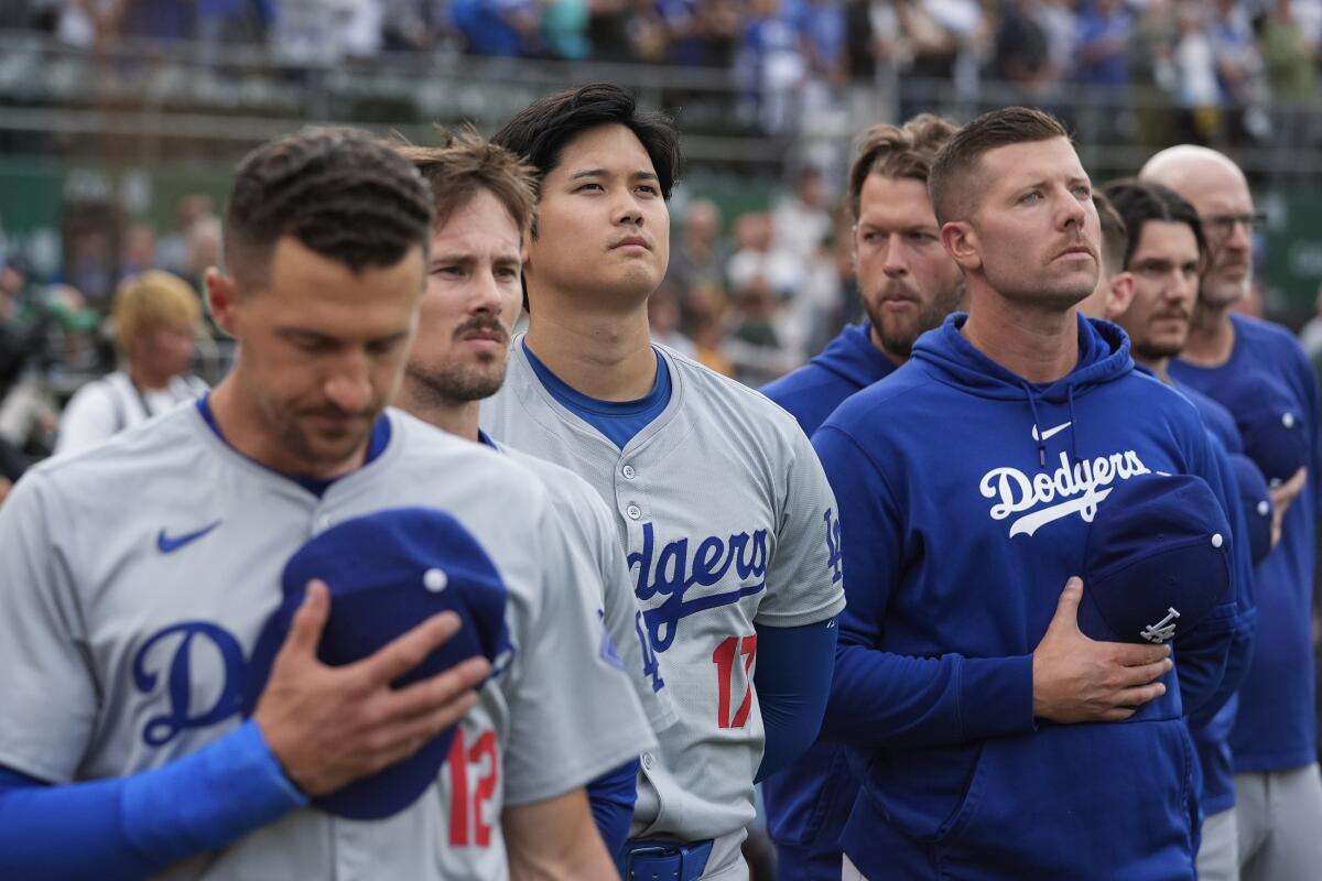 The Dodgers' Shohei Ohtani and teammates listen to the national anthem before playing the Athletics Friday in Oakland.
