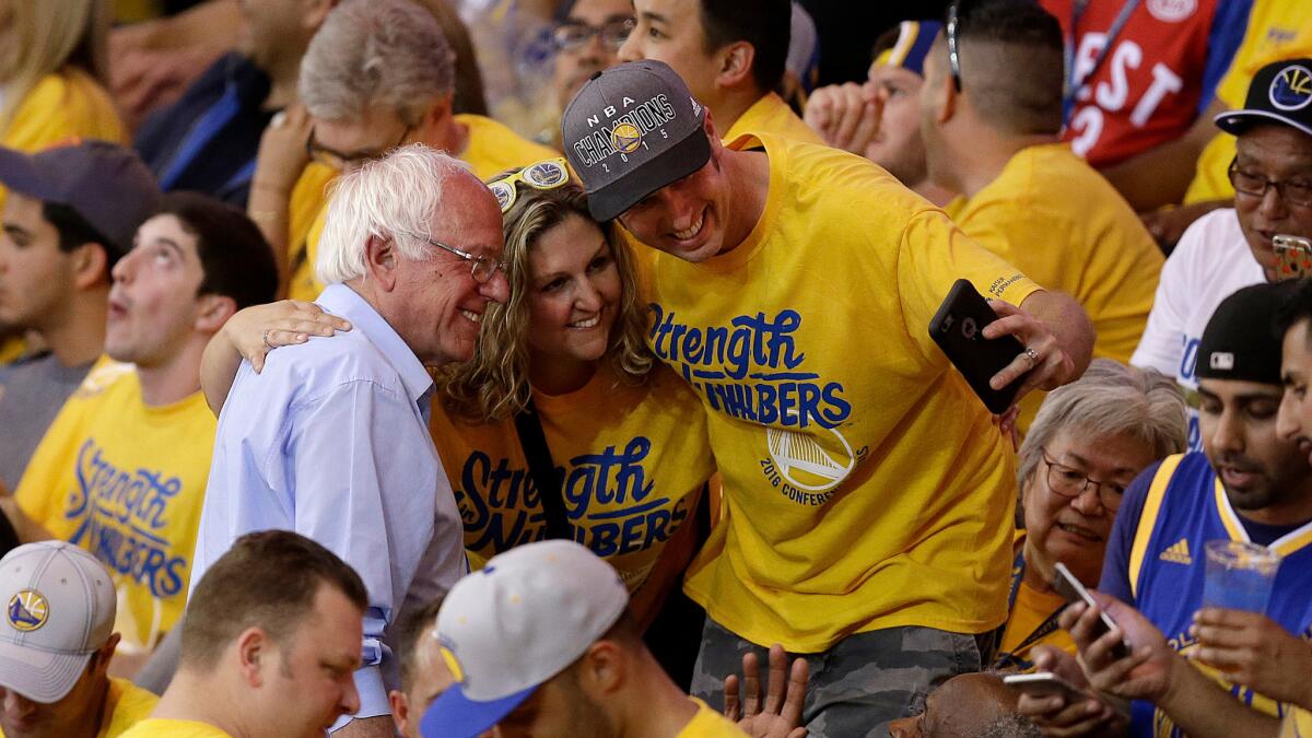 Democratic presidential candidate Sen. Bernie Sanders has his photo taken with fans during the NBA basketball playoff game between the Golden State Warriors and the Oklahoma City Thunder in Oakland, Calif. on May 30.