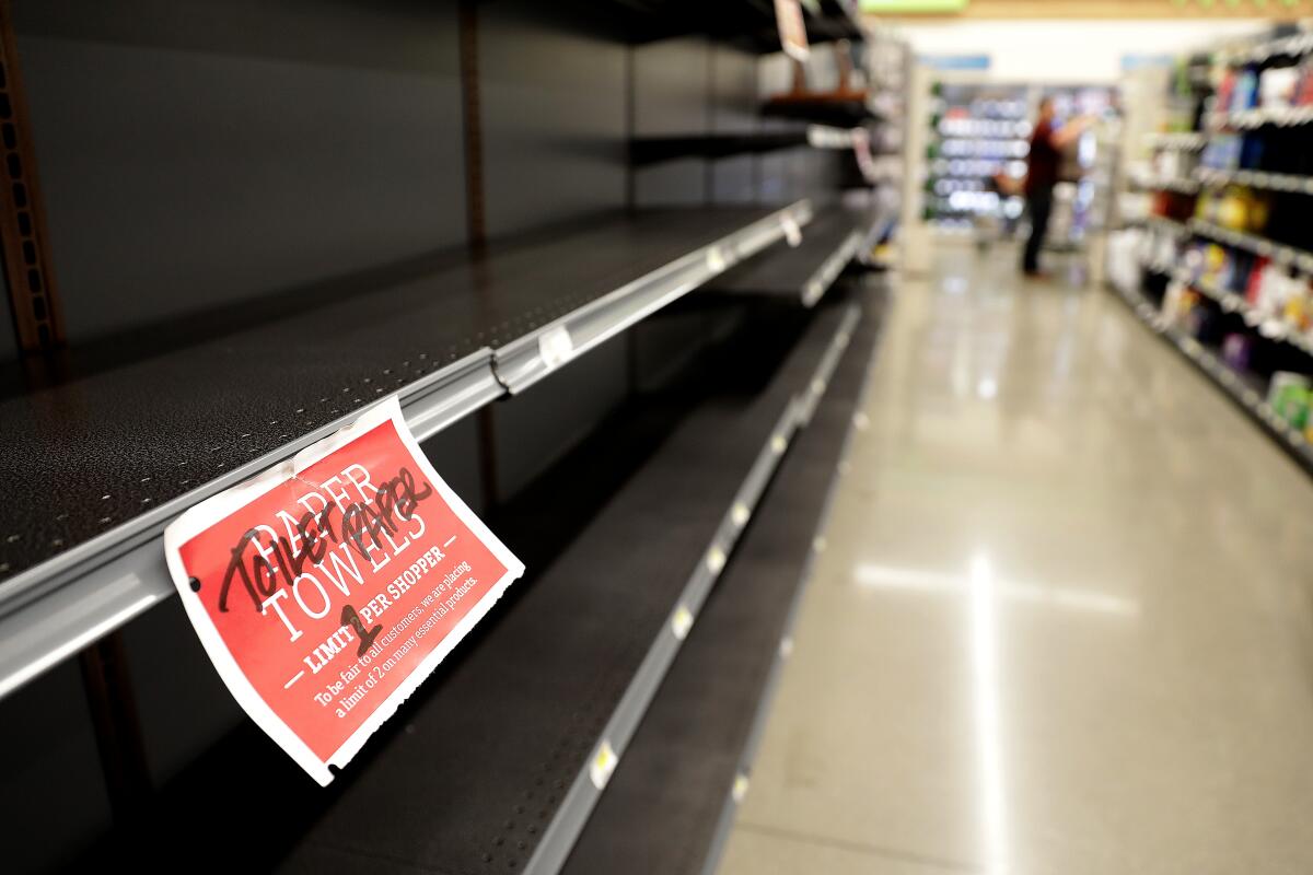 Empty shelves in a Manhattan Beach supermarket with a sign limiting one pack of toilet paper per shopper.