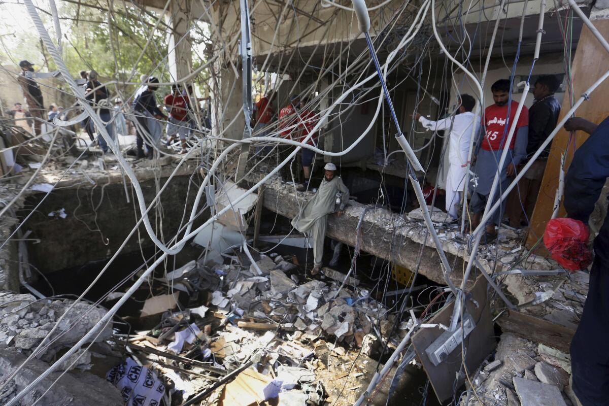 A web of cables dangles over rubble from a partially collapsed building where the floor has collapsed.