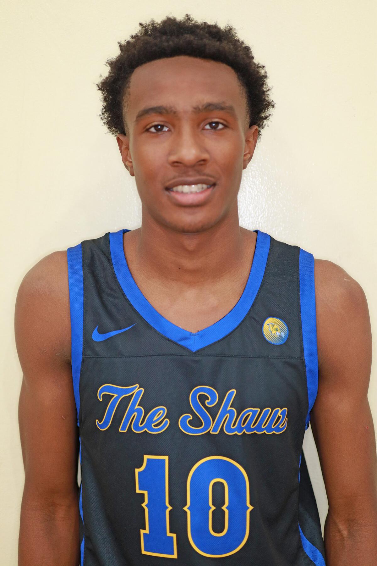 A vertical frame of Quincy Reese Jr., wearing a number 10 basketball jersey, posing for the camera, slightly smiling