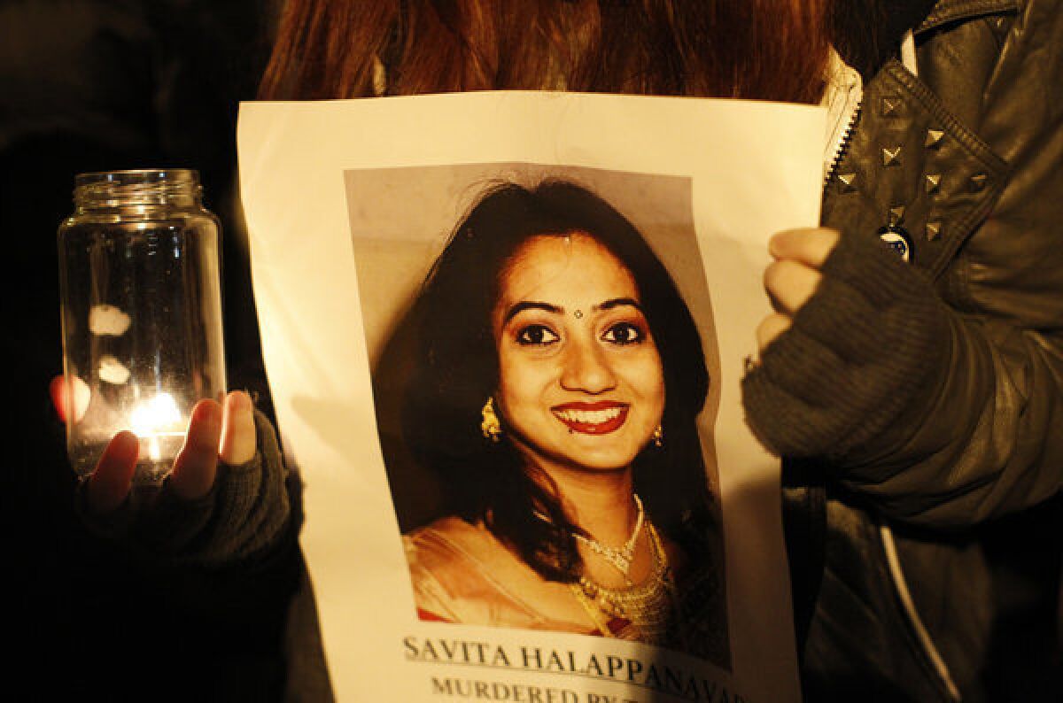 A woman holds a picture of Savita Halappanavar during a candle light vigil outside Belfast City Hall, Northern Ireland, on Thursday for Savita Halappanavar, who died of blood poisoning after suffering a miscarriage in Galway.