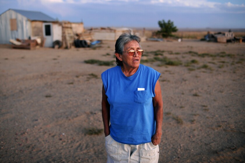 Navajo reservation resident Cynthia Dixon outside her trailer home in Fruitland, N.M., looking toward a coal mine in the distance. Residents in the area, including Dixon, blame the pollution from the mine and nearby power plants for health problems.