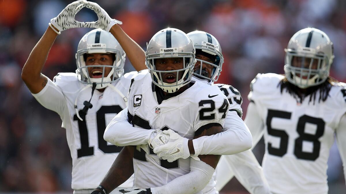 Raiders defensive back Charles Woodson (24) is hugged by teammate David Amerson (29) after intercepting a pass during the fourth quarter Sunday in Cleveland.