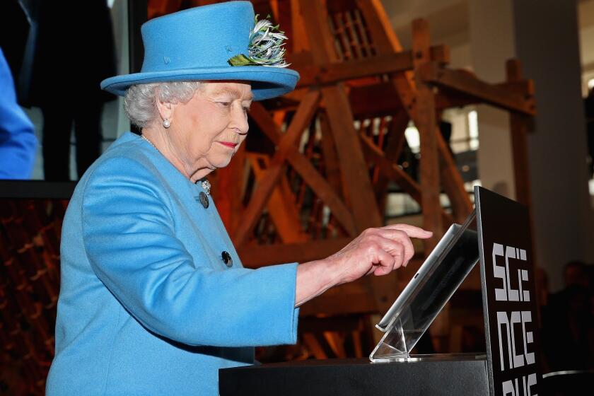 Britain's Queen Elizabeth II sends her first tweet at the opening of the "Information Age" exhibition at London's Science Museum on Oct. 24.