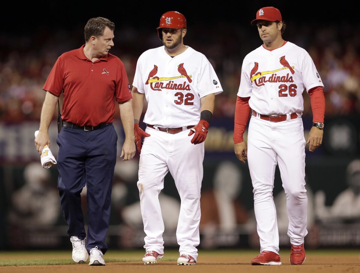 Cardinals first baseman Matt Adams (32) walks off the field with Cardinals trainer Chris Conroy and Manager Mike Matheny (26) after injuring his right leg.