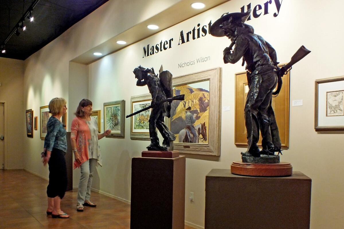 Director Karin Topping, right, explains the works of the community's master artists to a visitor at Tubac Center of the Arts.