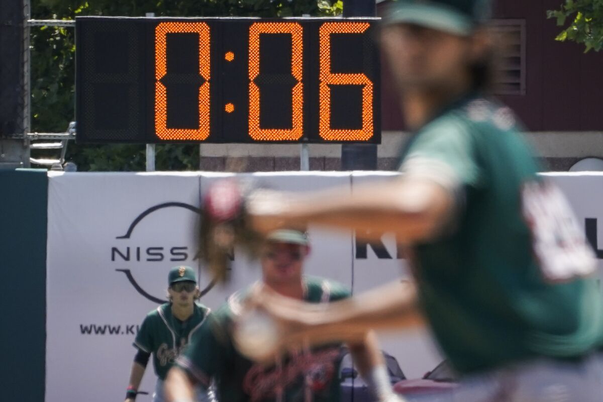 Un reloj lleva el tiempo que se toman los lanzadores para hacer un tiro durante un partido de las ligas 