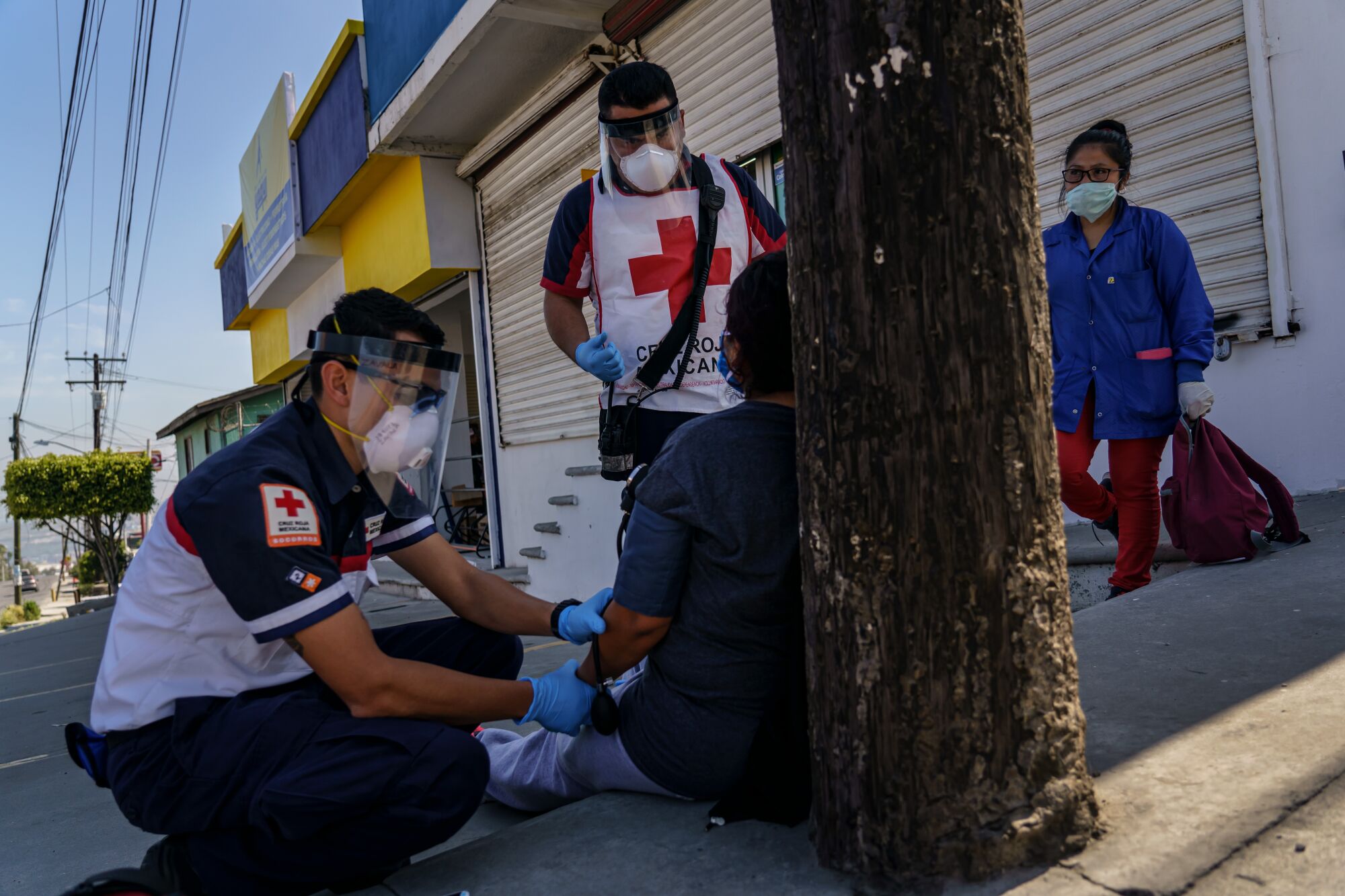 Los paramédicos de la Cruz Roja Michael Zavala, 22, izquierda, e Iván Mora, 33, arriba, administran atención a una paciente que ya había estado en el hospital por los síntomas de COVID-19, pero como su tasa de saturación de oxígeno sigue siendo del 99 por ciento, se le dijo que se quedara en casa y vigilara sus síntomas, para no abrumar a los hospitales encargados de tratar los casos de COVID-19, en Tijuana, México, el 2 de mayo de 2020.