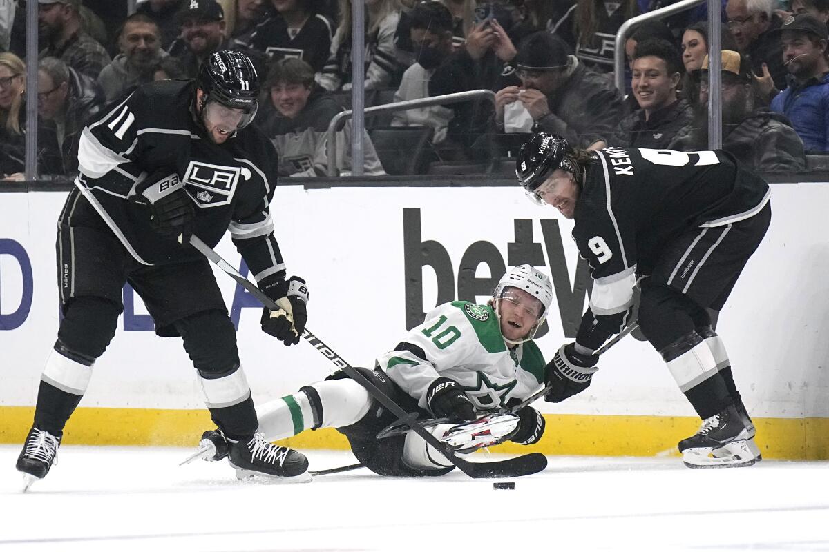 Dallas Stars center Ty Dellandrea falls as he battles for the puck with Kings' Anze Kopitar and Adrian Kempe.