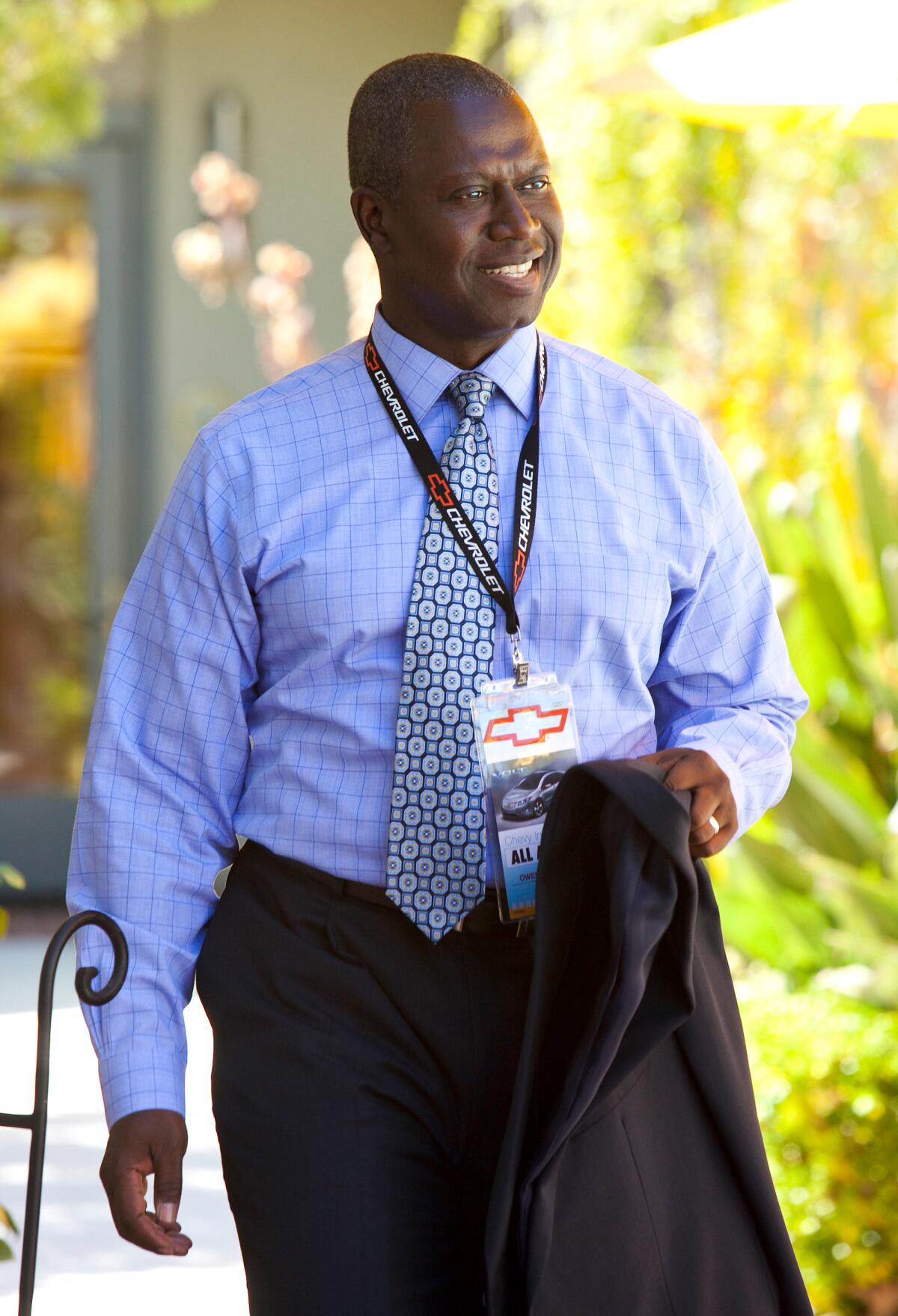 Andre Braugher as Owen walking outside in a shirt and tie with a lanyard around his neck.