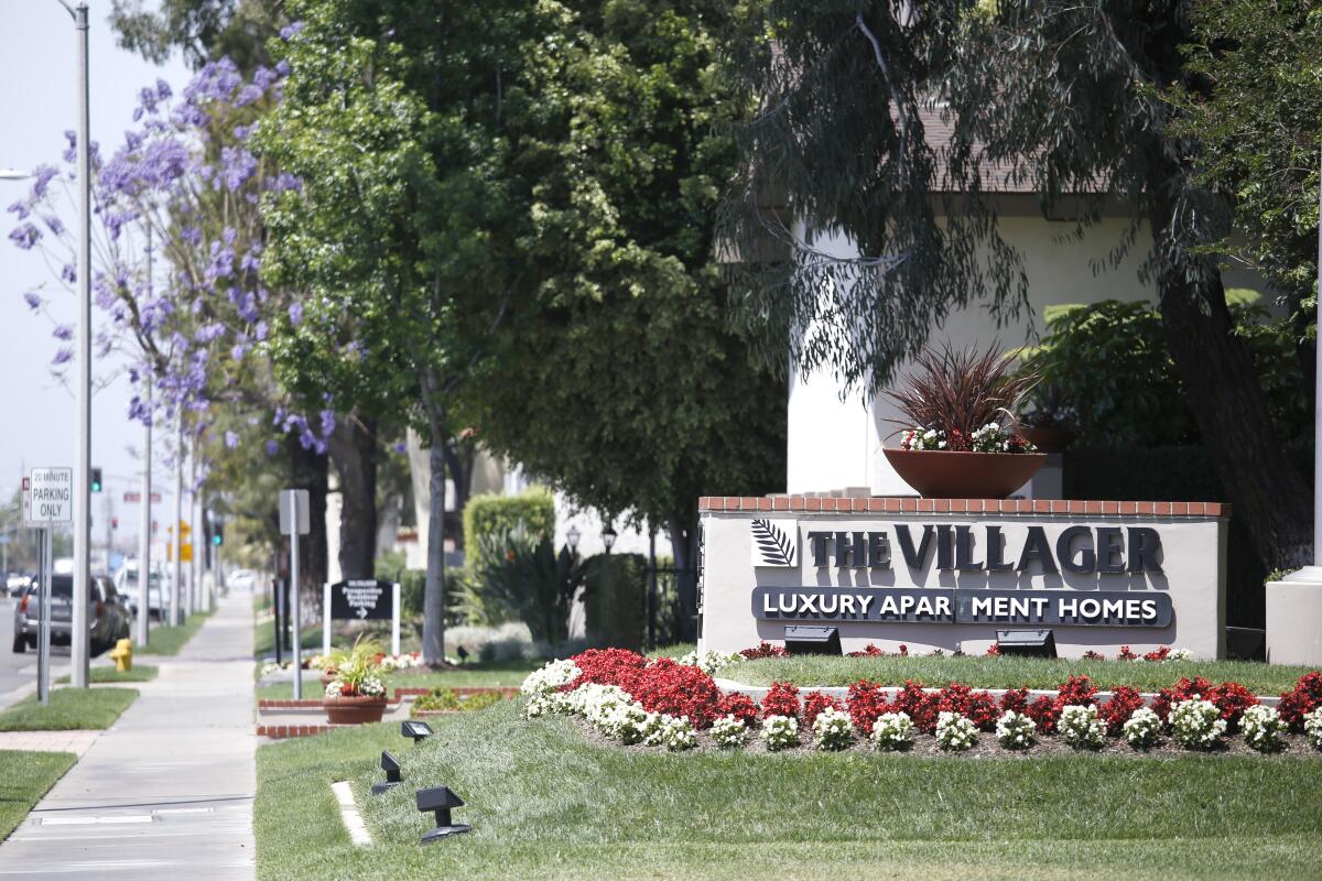 A sign on a lawn says "The Villager: Luxury Apartment Homes."