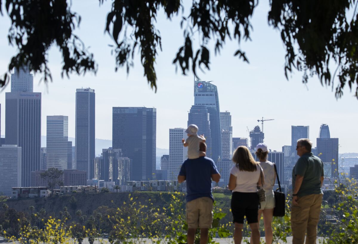 A group of five people look at the downtown Los Angeles skyline in the distance