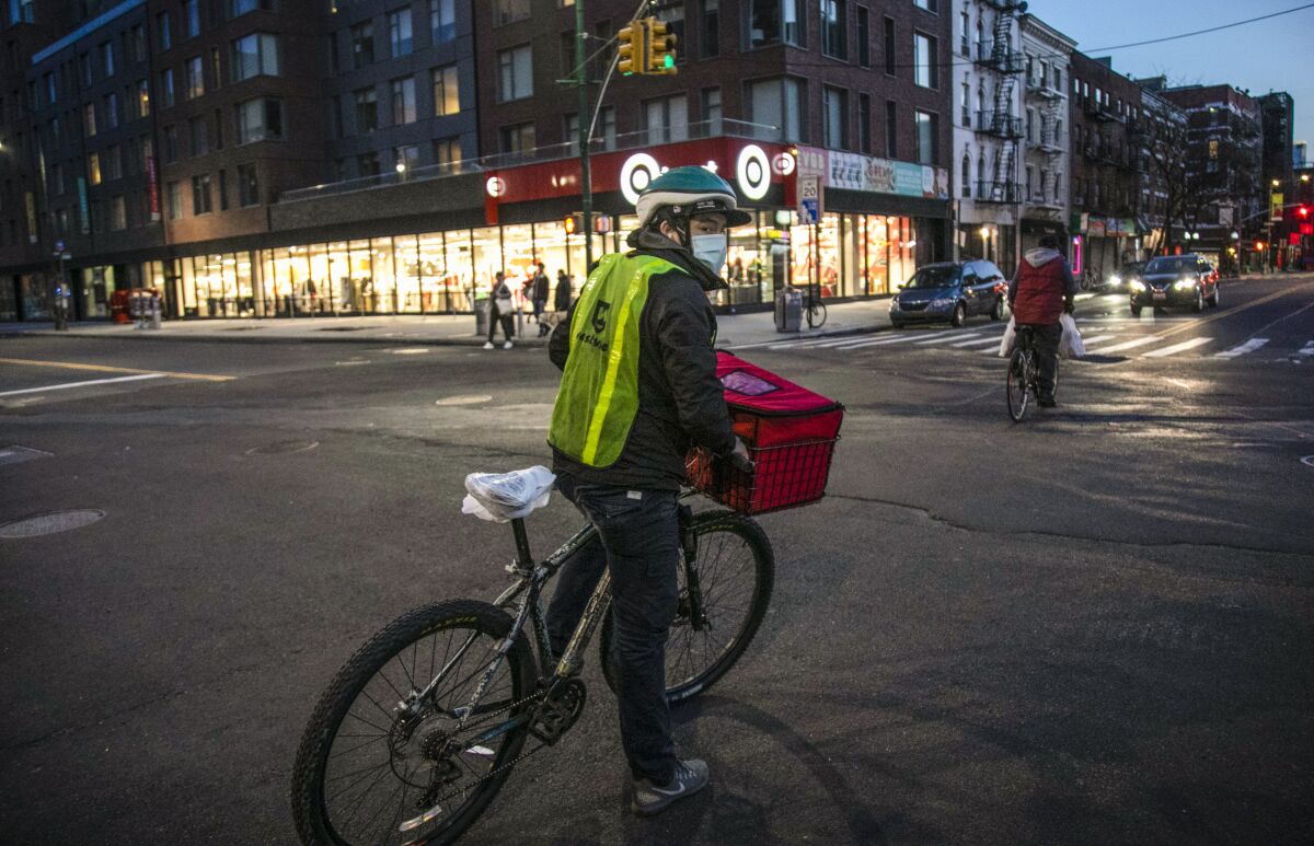 FILE - A cyclist delivering food stops at an intersection in the East Village neighborhood of New York, on Thursday, March 26, 2020. Food delivery workers and other app workers in New York City are pressing for protections including better wages, health care and the right to unionize. (AP Photo/Wong Maye-E, File)