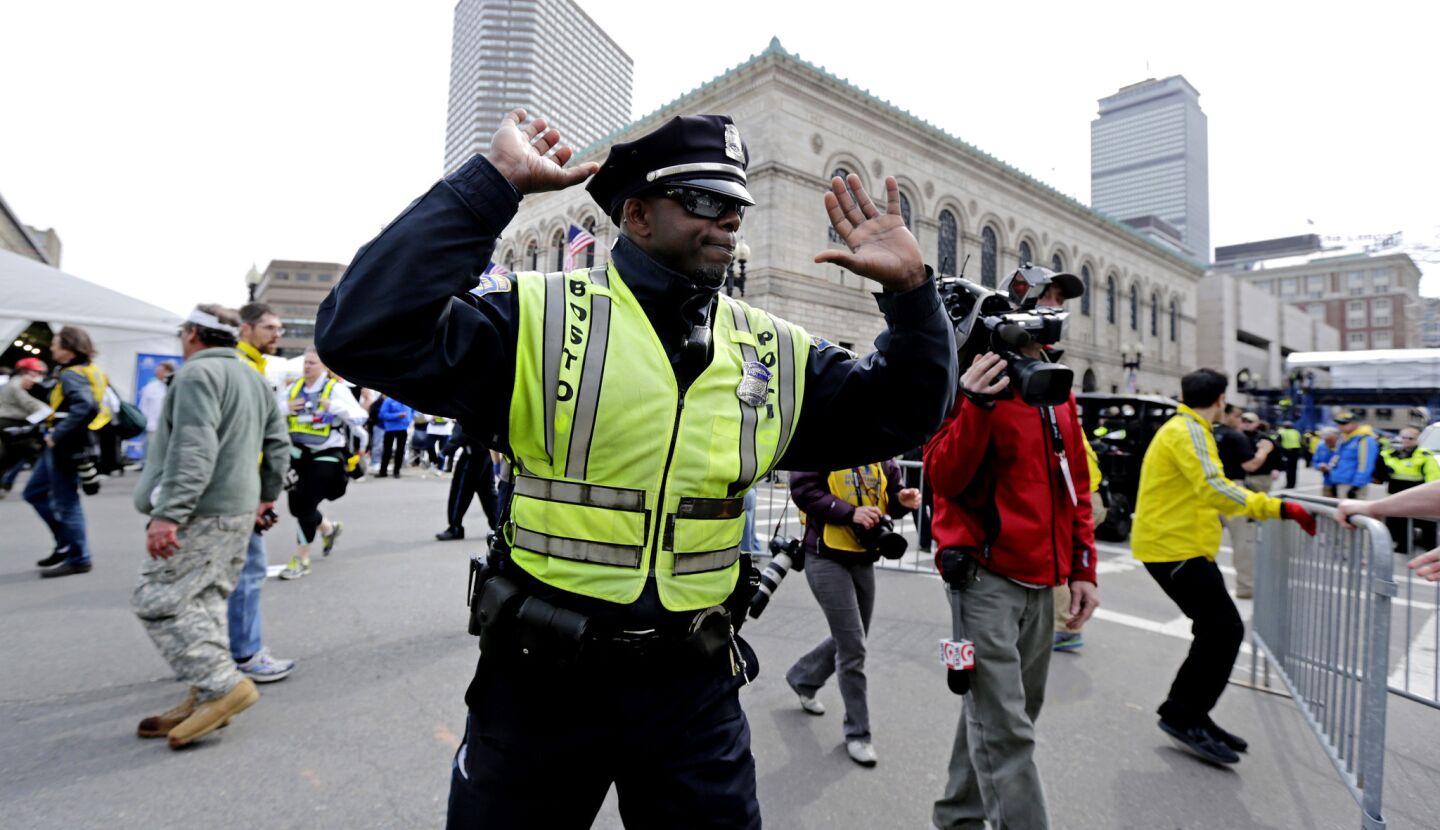 A Boston police officer clears Boylston Street after explosions at the finish line of the 2013 Boston Marathon.