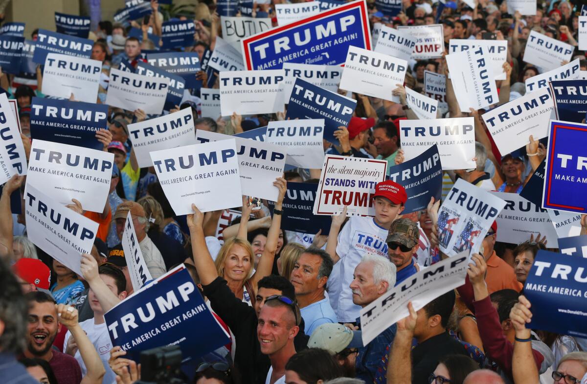 Audience members hold up signs supporting Donald Trump during a campaign rally in Boca Raton, Fla., on March 13.