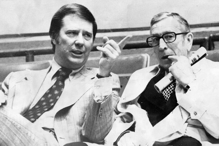 Coaches Bob Boyd, left, of USC and John Wooden of UCLA talk in the stands before a game in March 1974.