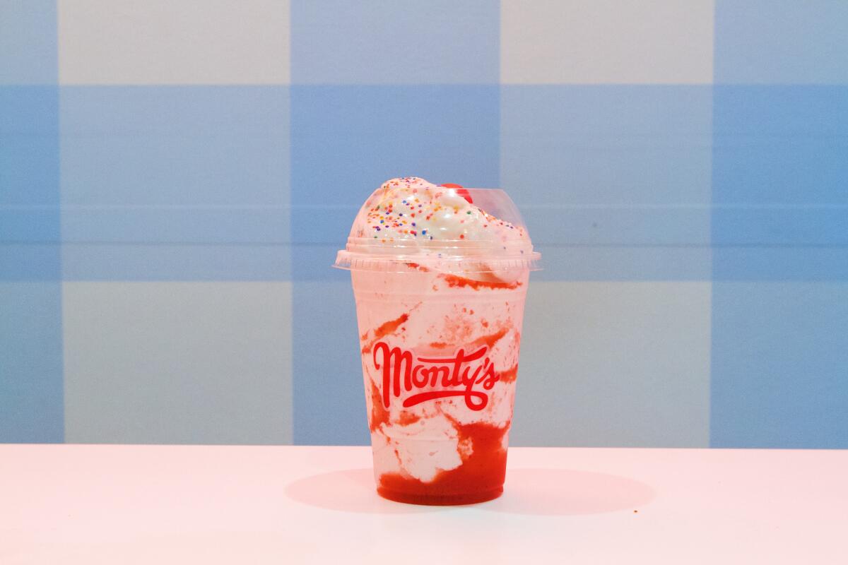 A sprinkle-topped strawberry milkshake against a blue-and-white-checked background