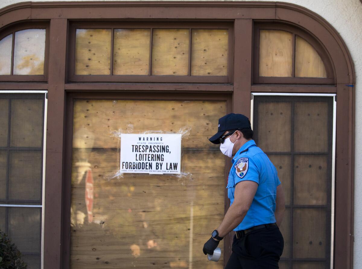 A security worker tapes up warning signs against trespassing at a  vacant home in the El Sereno neighborhood 