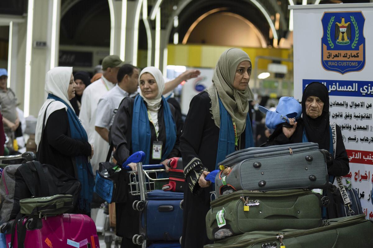 Iraqi pilgrims headed to Mecca for hajj push luggage carts at the Baghdad airport.