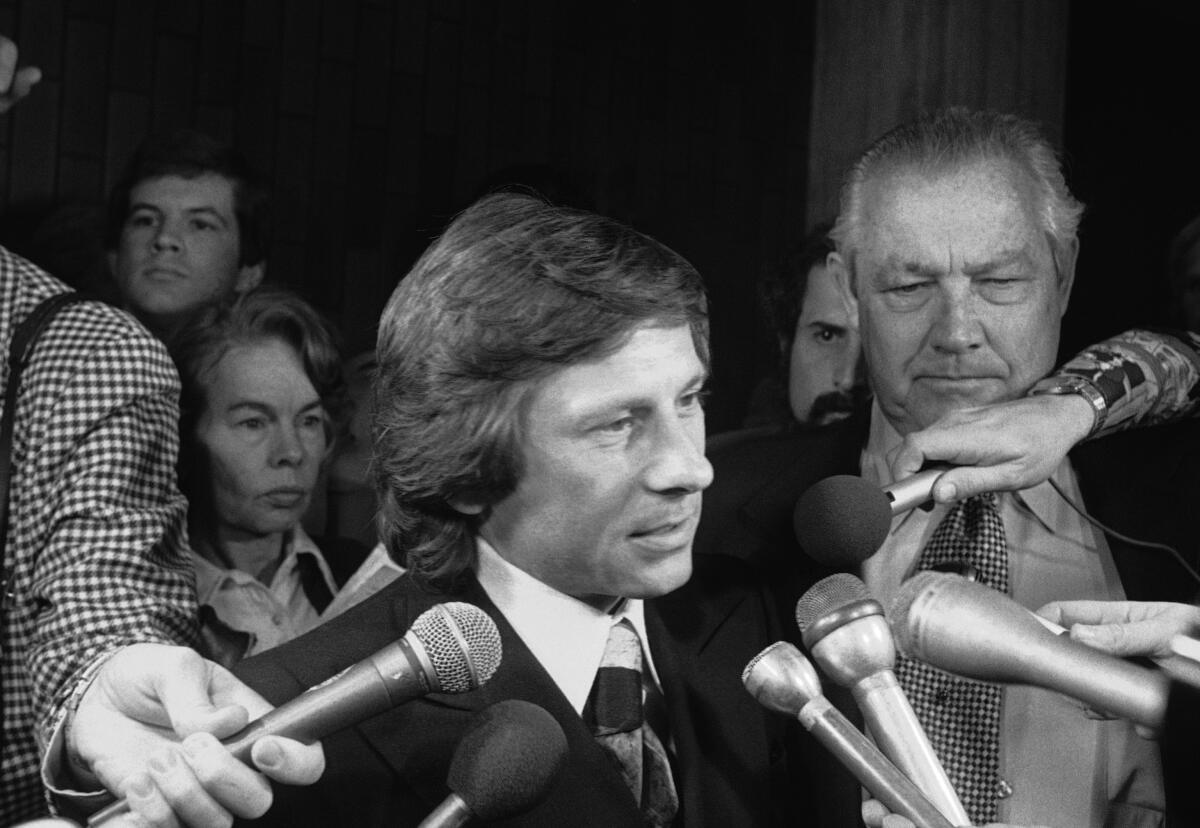 FILE - Movie director Roman Polanski talks with reporters outside the courtroom where he was arraigned on March 30, 1977, in Los Angeles, on rape and sex perversion charges. The case involving Polanski, who fled the United States after he forced himself on a 13-year-old girl during a photo shoot, has spanned 45 years. On Sunday, July 17, 2022, The Associated Press obtained an unsealed court transcript of the former prosecutor in the case testifying that the judge privately told lawyers he would renege on a promise and imprison the renowned director. (AP Photo/File)