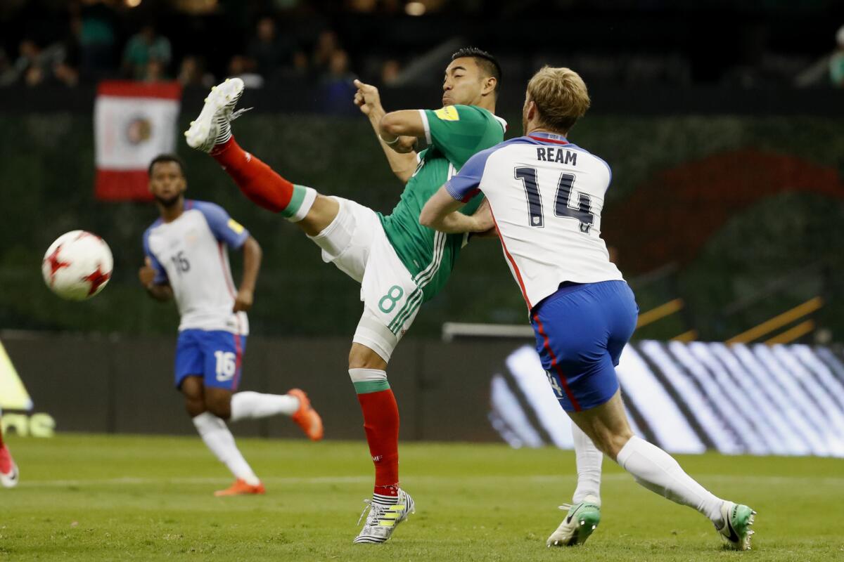 Mexico's Marco Fabian tries to volley a pass under pressure from U.S. defender Tim Ream.