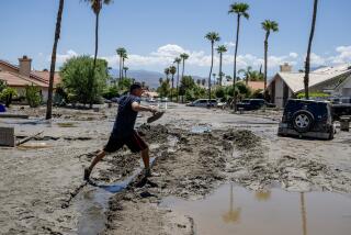 CATHEDRAL CITY, CA - AUGUST 22, 2023: Ronald Mendiola walks barefoot through the mud after checking on his house on Horizon Road on August 22, 2023 in Cathedral City, California. He and his family had to climb onto their roof to escape the flood waters from tropical storm Hilary Sunday night. Jimmy Laker, a local resident rescued the Mendiola family from the rooftop with his four wheel drive truck..(Gina Ferazzi / Los Angeles Times)
