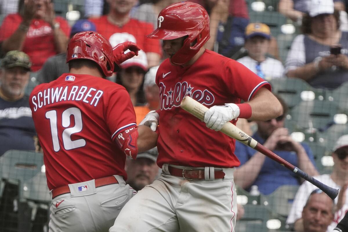 Philadelphia Phillies' Kyle Schwarber is congratulated bt Rhys Hoskins after hitting a two-run home run during the eighth inning of a baseball game against the Milwaukee Brewers Thursday, June 9, 2022, in Milwaukee. (AP Photo/Morry Gash)
