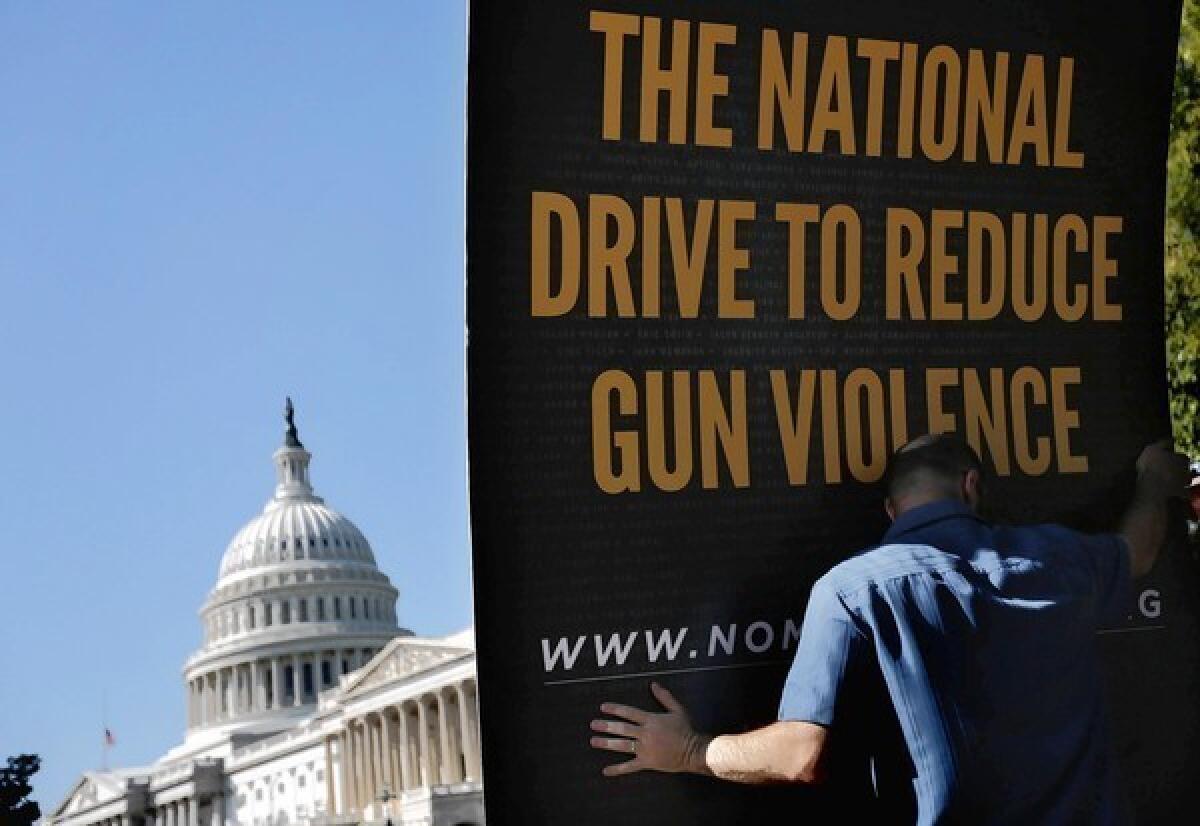 A worker sets up a sign on Capitol Hill for Mayors Against Illegal Guns, which is fighting for an improved background check system.