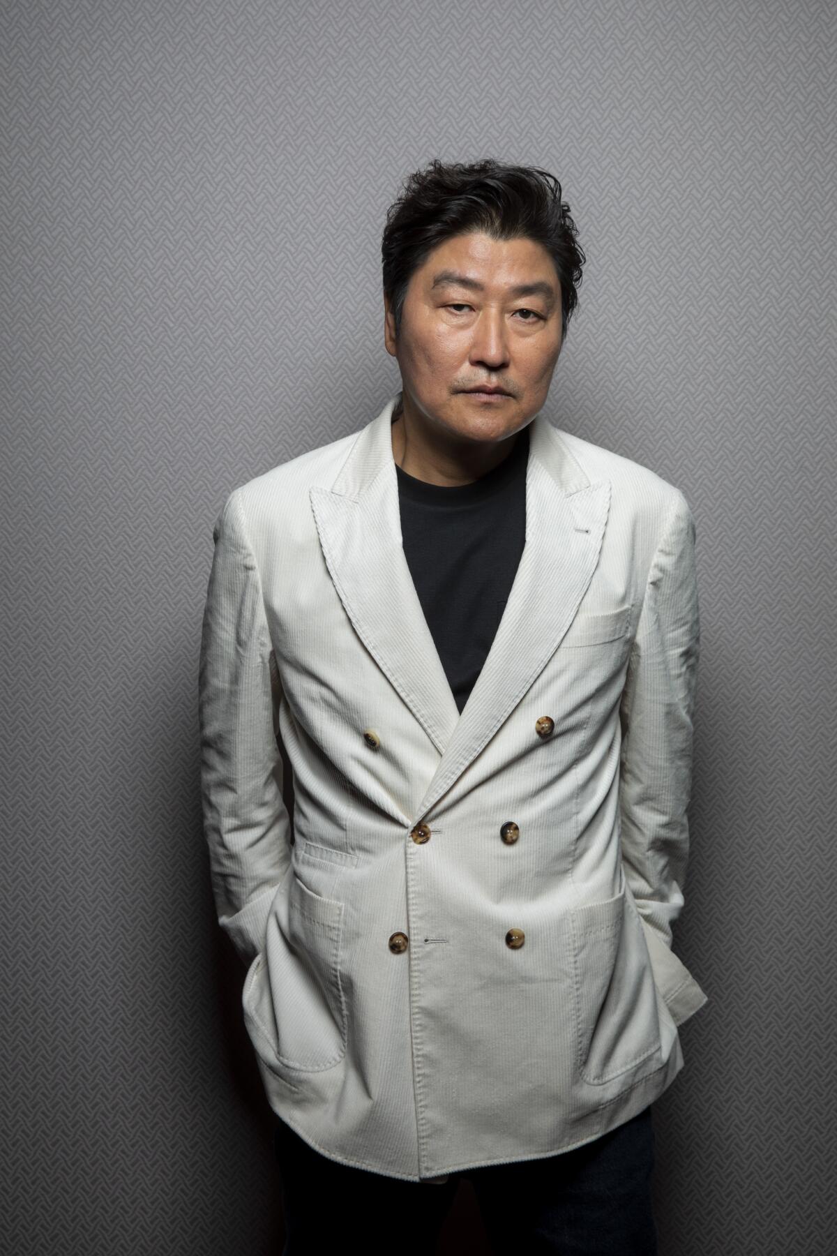 A man in a white blazer poses for the camera.