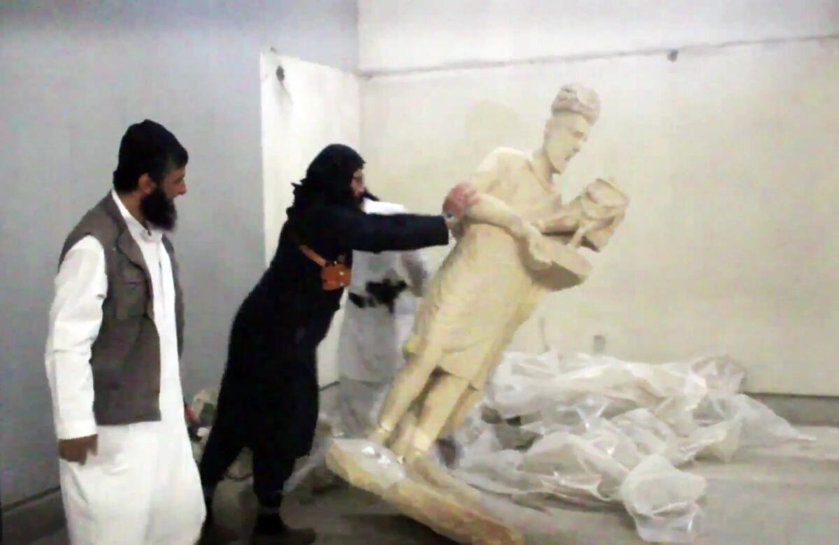 In this image taken from video, a militant topples an ancient statue at the Ninevah Museum in Mosul, Iraq.