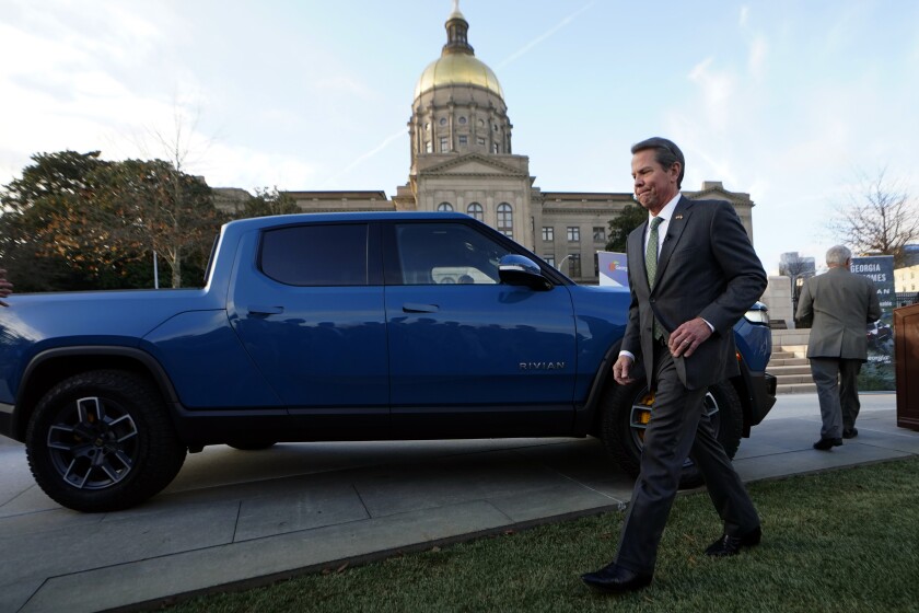 Gov. Brian Kemp walks past a Rivian electric truck after announcing that electric truck maker Rivian Automotive will build a $5 billion battery and assembly plant east of Atlanta projected to employ 7,500 workers, Thursday, Dec. 16, 2021, in Atlanta. (AP Photo/John Bazemore)
