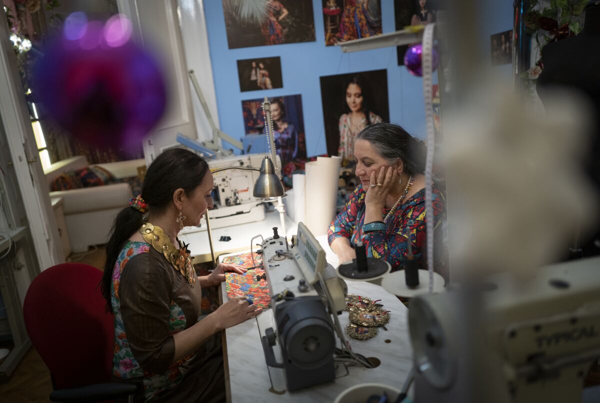 Roma sisters Helena, left, and Erika Varga work on a production in their fashion studio, Romani Design, in Budapest, Hungary, Sunday, Dec. 12, 2021. Romani Design, a fashion studio in Hungary, is challenging the centuries-old stereotypes faced by the country's Roma minority, and asserting a place at the table of high culture for the historically marginalized group. (AP Photo/Bela Szandelszky)