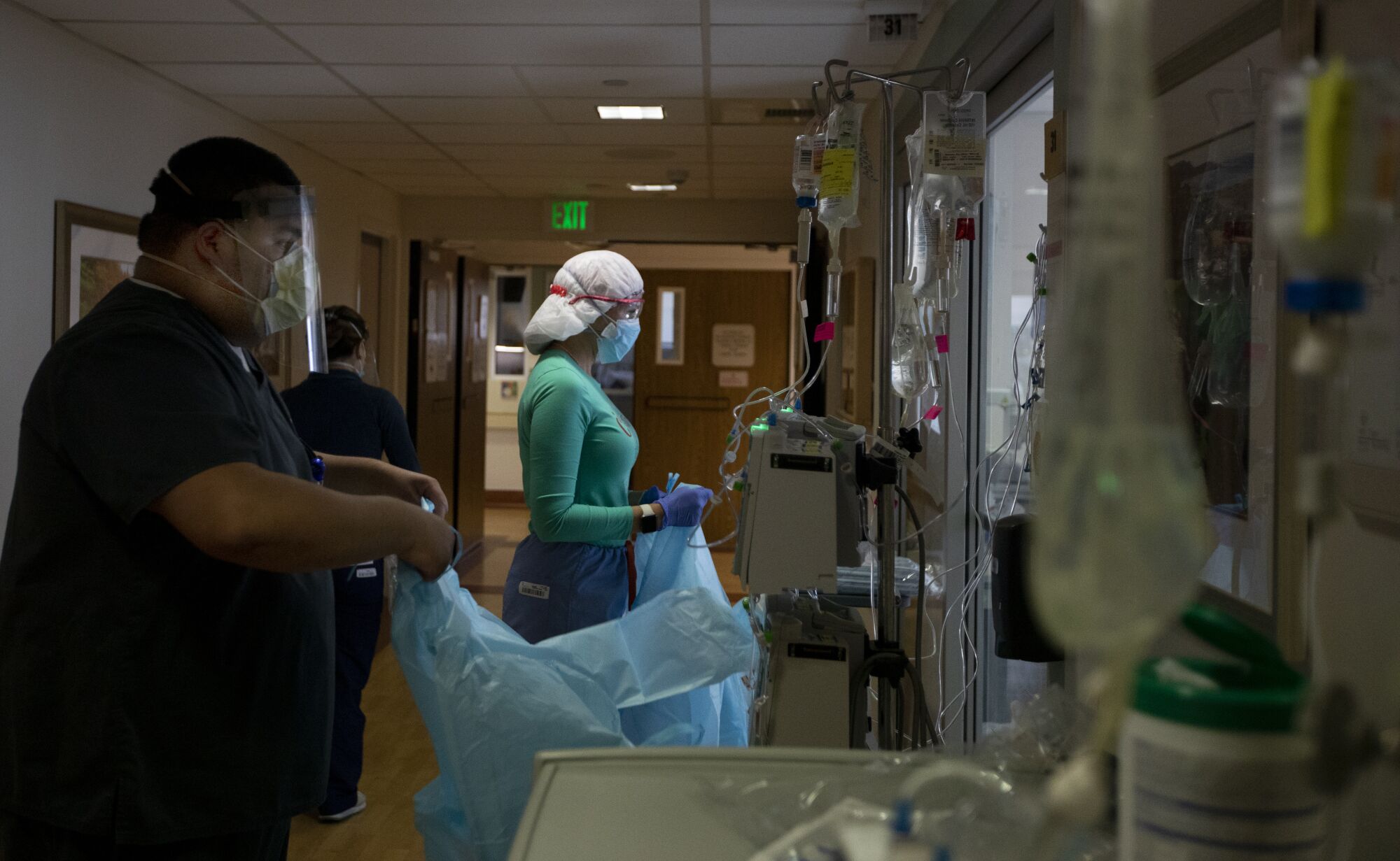 Daniel Guerrero, left, and RN Joan Pung don their isolation gowns
