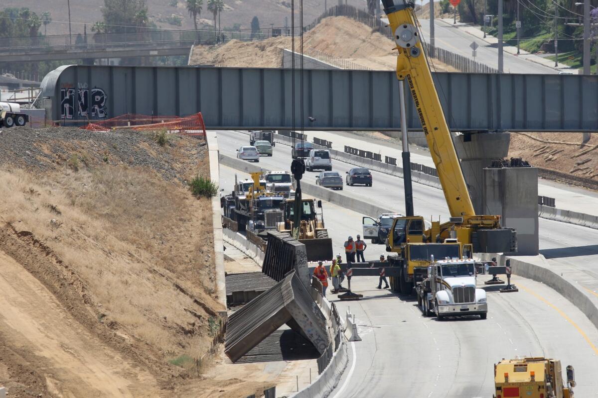 Workers clear debris from the 91 Freeway in Riverside after a railroad bridge collapsed, killing a worker and snarling traffic.