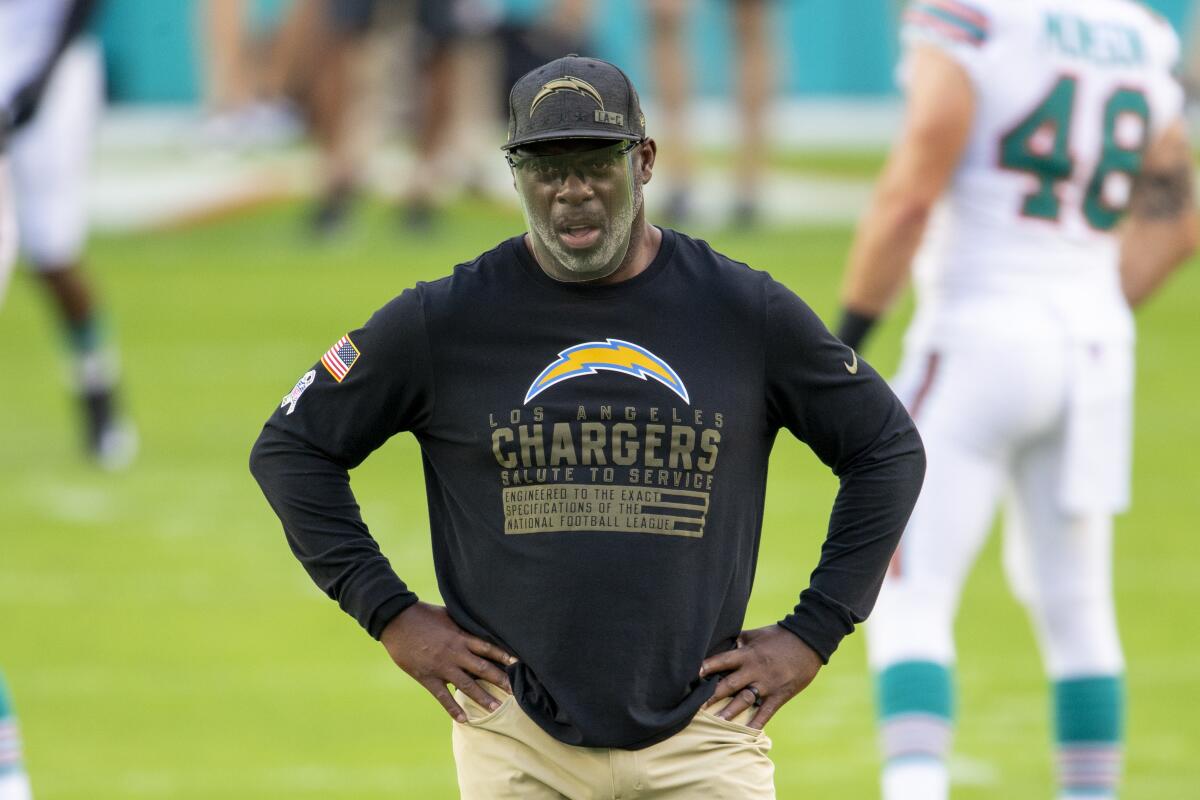 Chargers coach Anthony Lynn stands on a field.