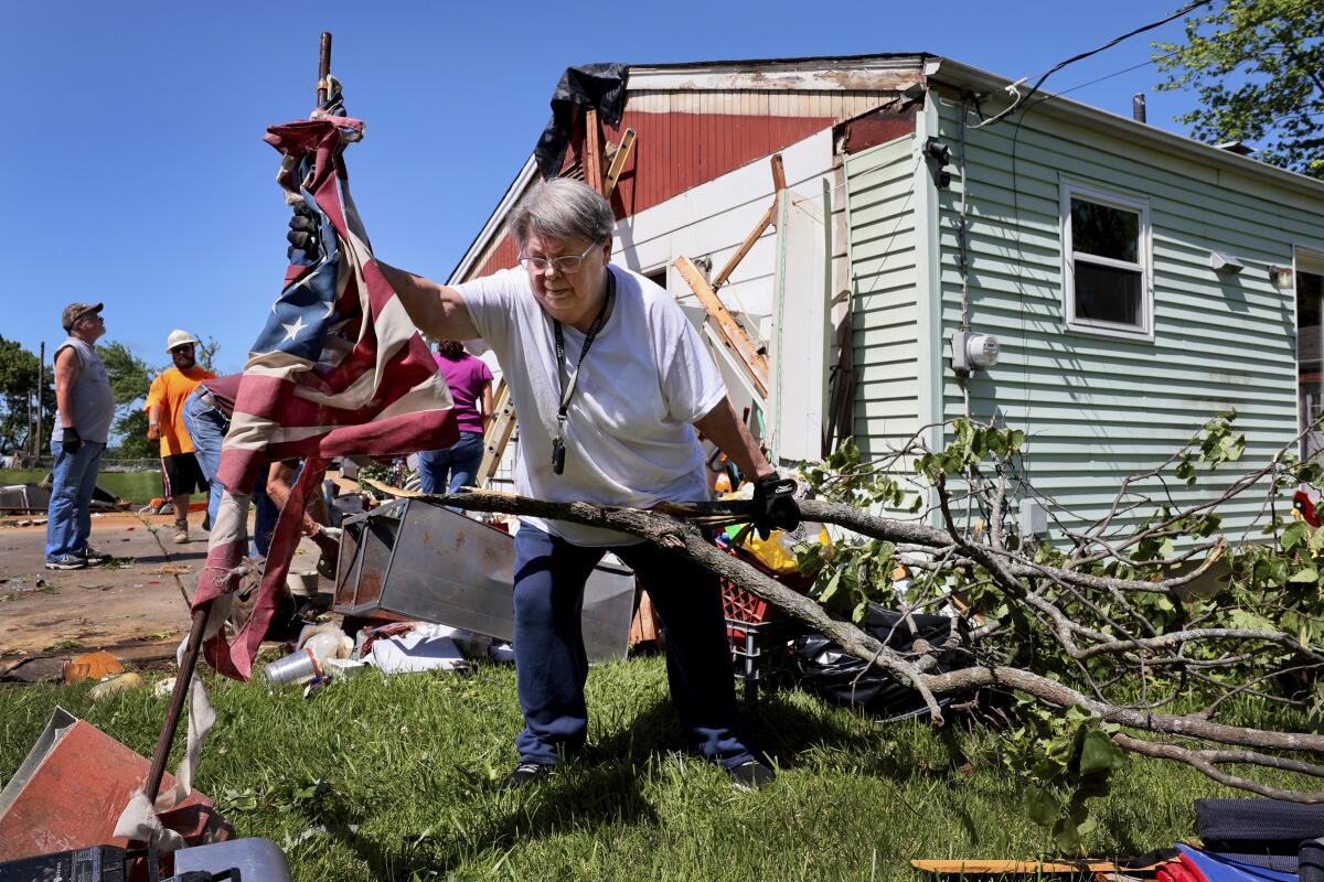 A woman recovering a shredded American flag while gathering downed tree branches