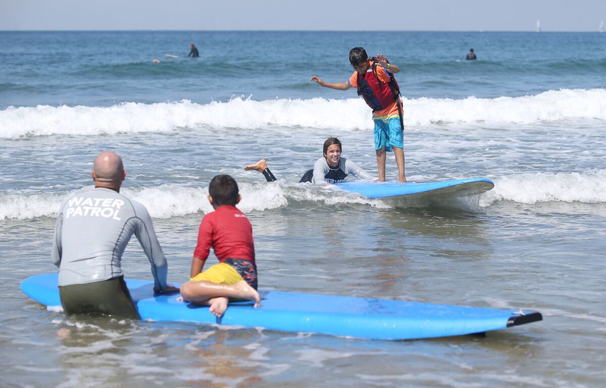 Kenneth Avendano gets to his feet at Friday's Miracles for Kids surf camp in Newport Beach.