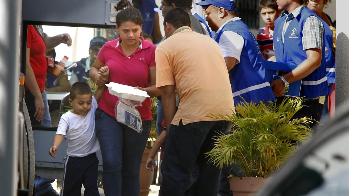 A mother from the first planeload of Honduran women and children who were deported from the U.S. leads her son toward a bus at the Center for Returned Migrants in San Pedro Sula, Honduras, on Monday.