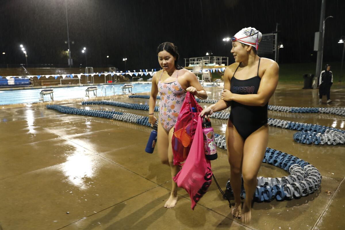 La Mirada Armada swimmers Kayla Han, left, and Sabrina Benanni, right, leave after a workout on a cold and rainy day.