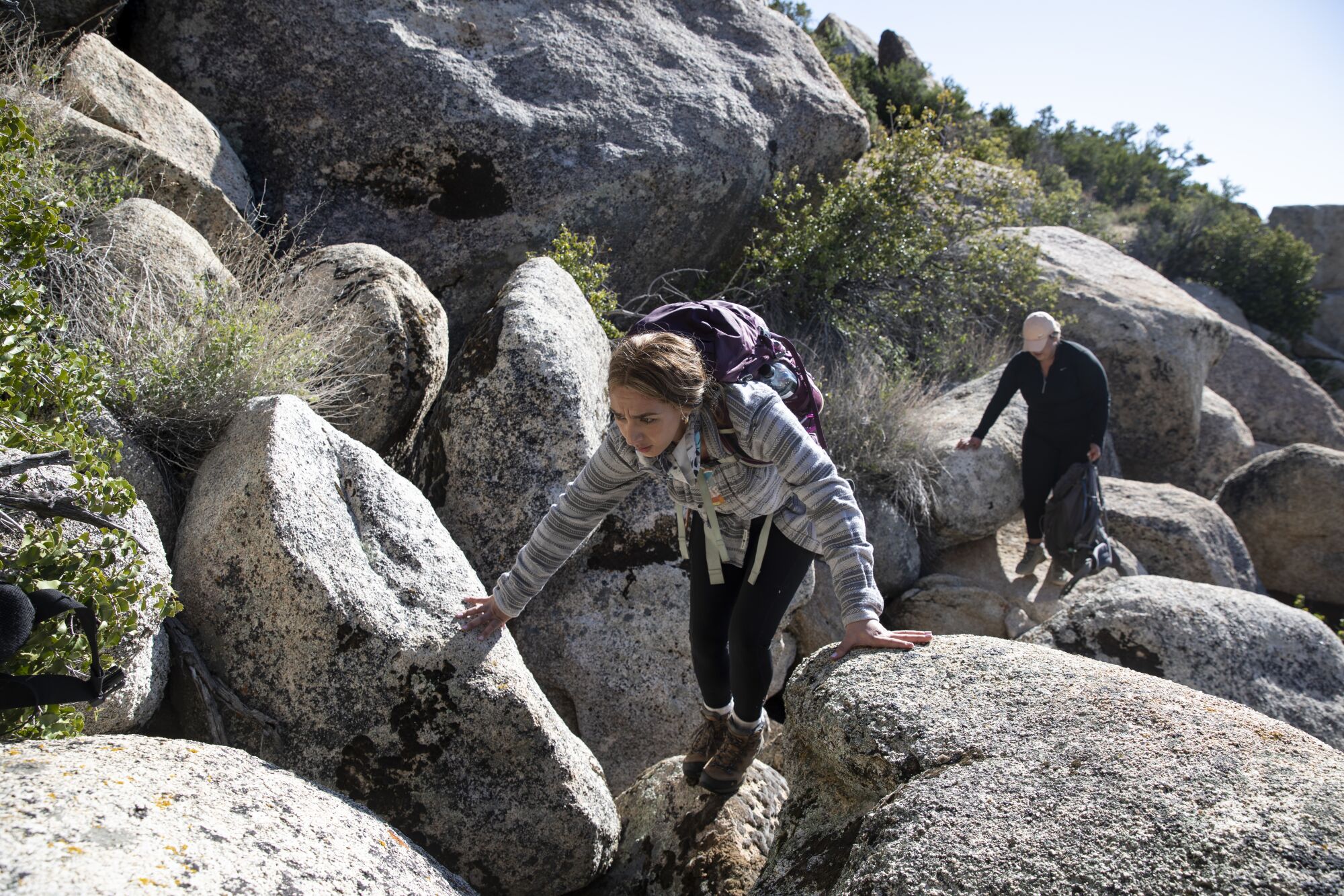 Armida Gomez and Jessica Gonzalez scramble over boulders on April 23, 2022, in a rugged area southeast of Mount Laguna.