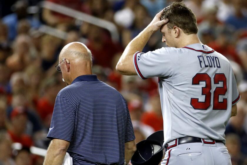 Braves starting pitcher Gavin Floyd walks off the field with Braves trainer Jeff Porter after injuring his elbow in the seventh inning of a game against the Washington Nationals on Thursday.