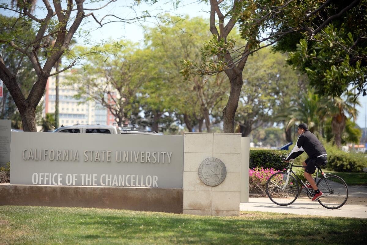 A bicyclist rides near a sign that says California State University Office of the Chancellor.