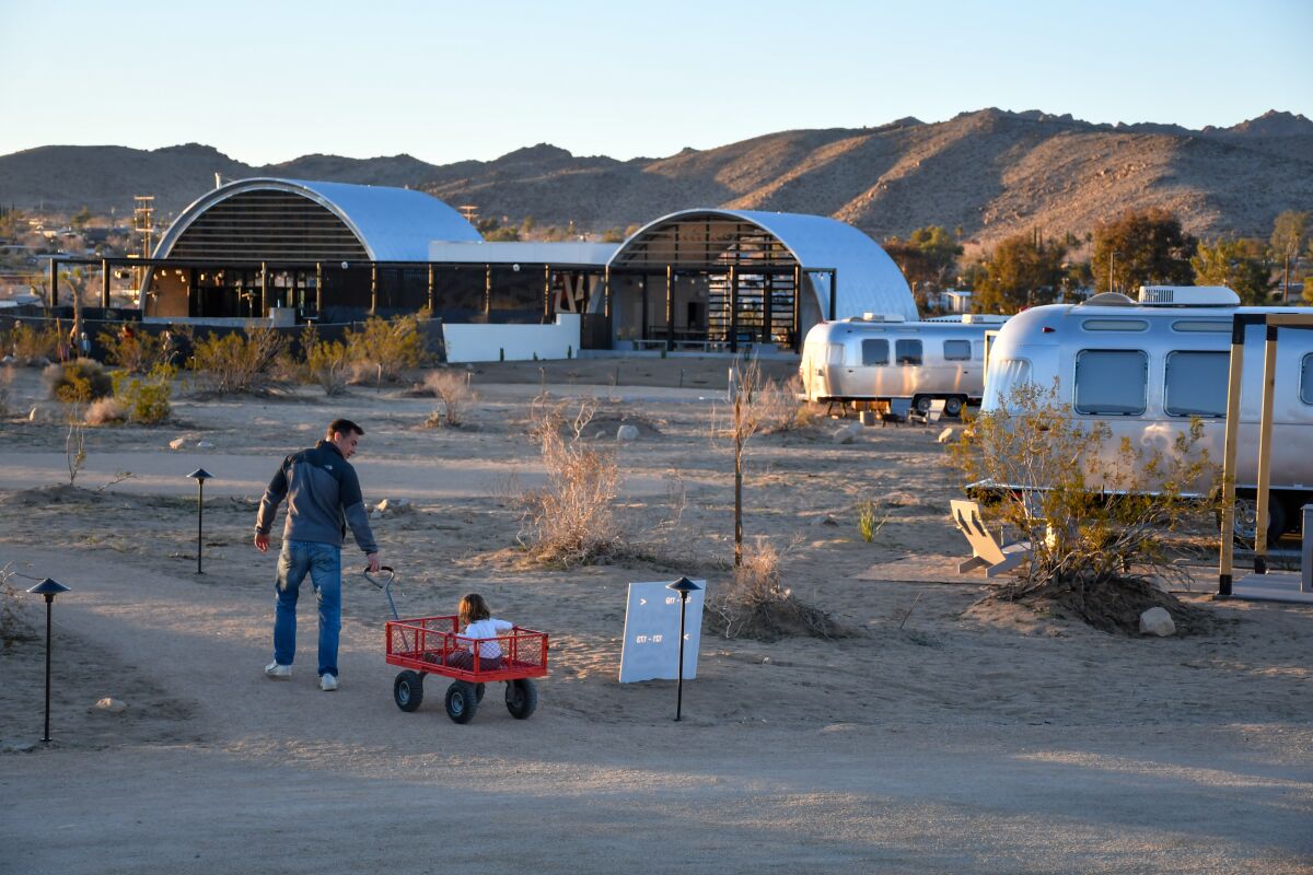 A man pulls a child in a wagon on the AutoCamp property.