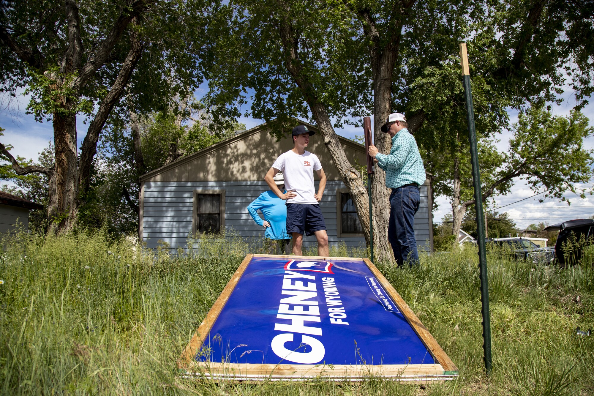 People stand next to a large blue "Cheney" sign before it's assembled