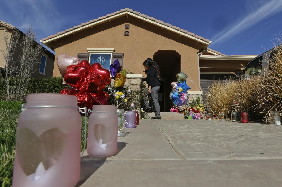 A view from down the driveway of neighbors placing messages near the front door of a house